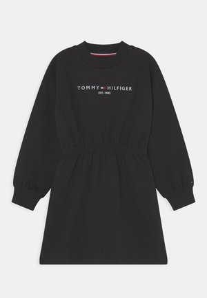 Zwarte jurk met lange mouwen, elastische taille, geribde manchetten, ronde hals en "Tommy Hilfiger Est. 1985" logo op de borst.