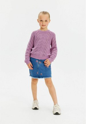Lilac adīta džempera ar teksturētu rakstu, apvienots ar zilu denim džinsu svārku, kurā ir varavīksnes izšuvums un nolobīts apakšmalas, nēsāts ar baltām kedām.