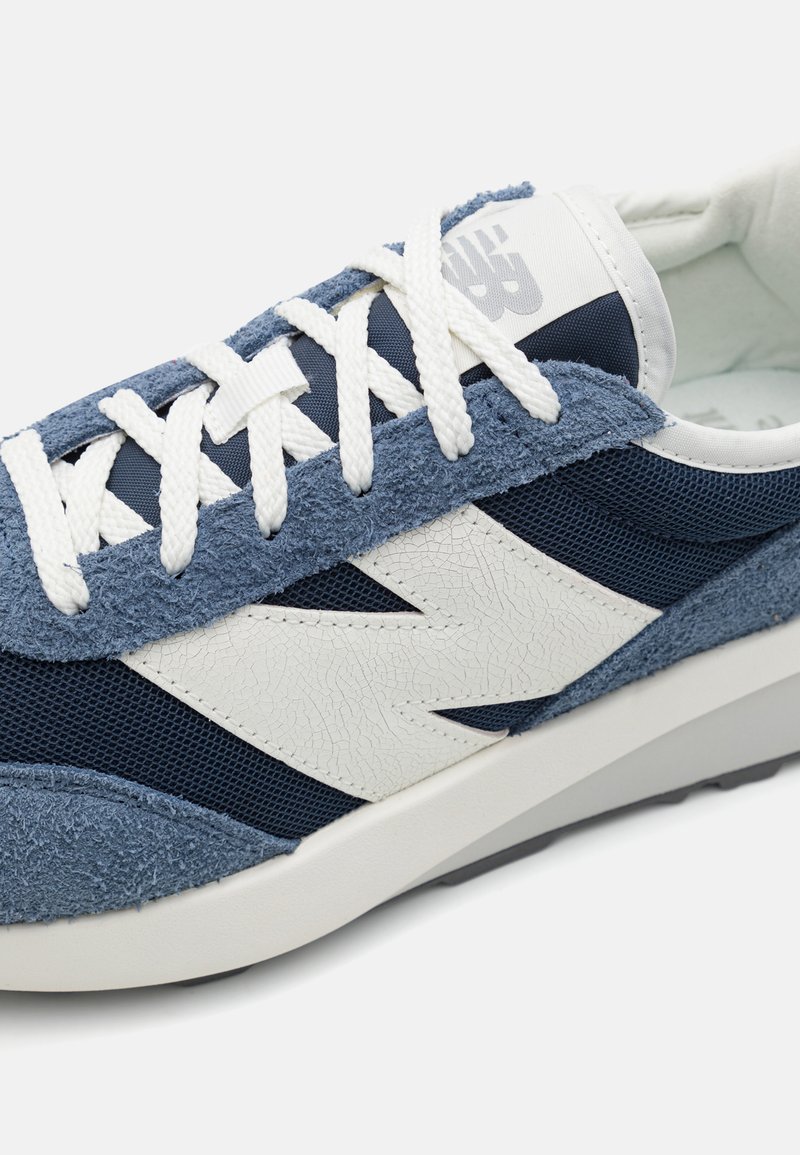 Blaue Wildleder- und Mesh-Sneaker mit weißen Akzenten und Schnürsenkeln. Verfügt über strukturierte Oberflächen, eine runde Zehenpartie und eine kontrastierende Sohle.