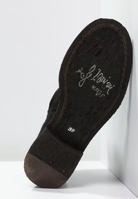 Suela de zapato de cuero negro con el nombre de la marca "Yellowai" y el número de talla 39 impresos en la suela y el tacón desgastados y suaves.