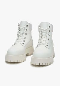 Witte veterschoenen met een stevige platformzool, gemaakt van glad materiaal, met ronde neuzen en metalen ogen voor de veters.