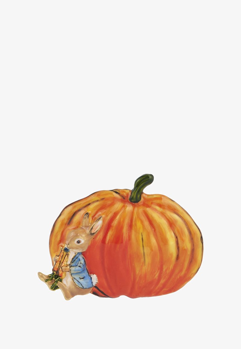 Keramička bundeva u narančasto s zelenim stabljikom, uz nju sjedi zec u plavoj jakni koji svira flautu. Vidljivi su detalji i tekstura.