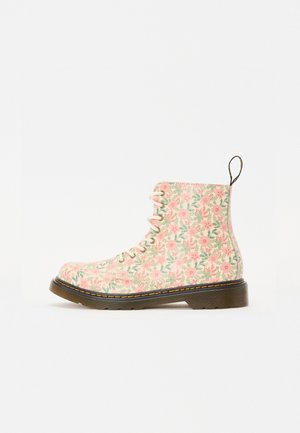 Høj sko med snørebånd med pink og grønt blomsterprint, sort sål, gule syninger og hælløkke på hvid baggrund.