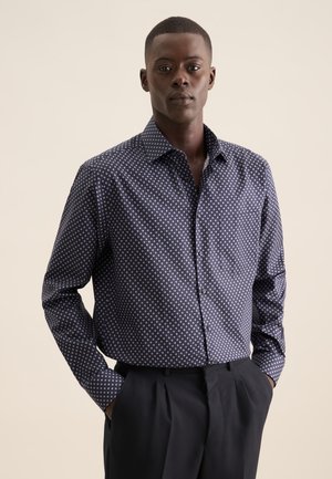 Chemise boutonnée bleu marine à motifs avec des formes de diamants blancs, à manches longues et col classique. Poche sur le côté gauche.