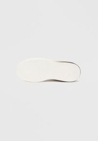 Bijela potplat tenisica s teksturiranom gumom koja ima valovite uzorke, glatke rubove i minimalistički dizajn.