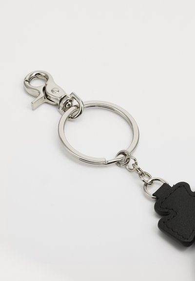 Metall-Schlüsselanhänger mit einem silbernen Clip und einem runden Ring, ausgestattet mit einem schwarzen Leder-Bärenanhänger mit gestickten Details.