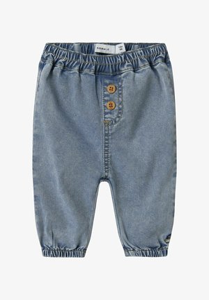 Pantaloni in denim blu chiaro con cintura elastica, dotati di due bottoni in legno e polsini elastici alle caviglie. Design classico a cinque tasche.