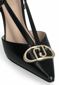 Scarpa nera in pelle con tacchi alti, punta affusolata e dettaglio con fibbia ovale color oro sulla tomaia. Design elegante con cinturini e texture liscia.