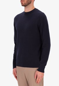 Pullover blu navy con collo rotondo realizzato in morbida lana. Vestibilità regolare con polsini e orlo a coste. Design semplice senza motivi visibili.