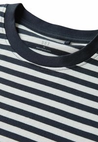 Svītru krekls kokvilnas maisījumā ar tumši zilu un baltu horizontālu svītru, apaļu apkakli un etiķeti ar uzrakstu "SET, M, MADE IN BANGLADESH."