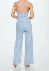 Jumpsuit de denim de color azul claro con diseño de pierna ancha, tirantes en la espalda en forma de cruz y detalles de costura sutiles. Textura suave y aspecto casual.