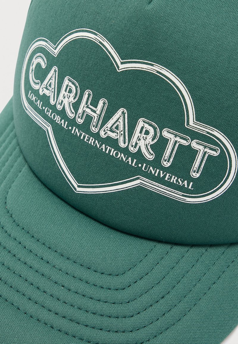 Casquette de baseball en tissu vert avec logo Carhartt blanc et texte indiquant "Local, Global, International, Universel" à l'intérieur d'un contour de nuage.