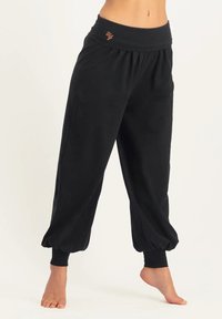 Schwarze, lässige Hose aus weichem Stoff. Mit einem breiten Bund mit Raffung und umschlagenen Knöcheln. Dezentes Logo in Orange.