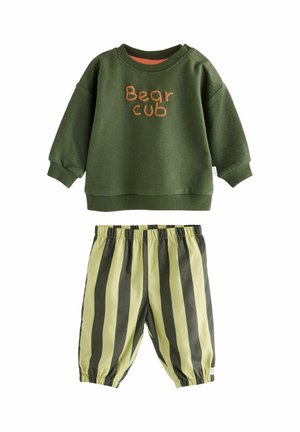 Green long-sleeve toddler shirt with "Bear cub" text paired with elastic waist pants featuring yellow and dark green vertical stripes.
