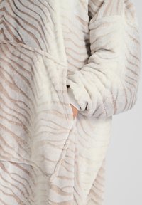 Oversized hoodie med zebra-mønster lavet af blødt, hvidt og lysebrunt plysstof, med ribbede manchetter og en frontlomme.