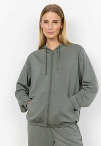 Khaki zip-up mikina z měkké, strukturovan�é tkaniny. Má kapuci se šnurkou, klokánkové kapsy a elastické manžety. Neformální a pohodlný design.