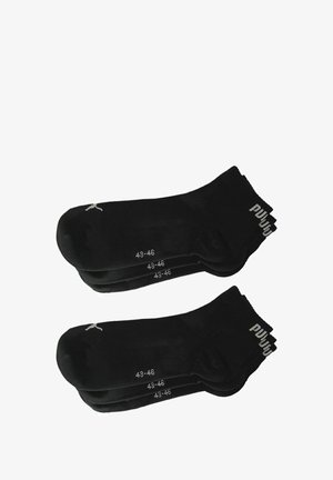 Black athletic socks in a pack of four, with size labels 43-46, featuring a ribbed cuff and minimalistic logo detail. Smooth texture.