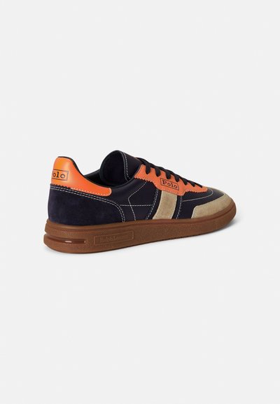 Tamsiai mėlynas ir oranžinis sportbačiai su zomšine ir odine viršutine dalimi, raišteliais priekyje, kontrastingais akcentais ir tekstūruota guminė pado danga.