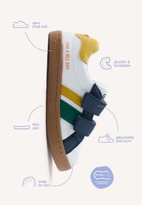 Zapatilla infantil con cierres ajustables, suela flexible, puntera ancha, suela fina con cero caída, rayas amarillas y verdes, y texto "¡Que tengas un buen día!".