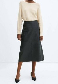 Jupe midi en cuir noir avec des lignes épurées et une texture lisse, associée à un pull en laine beige. Design simple et minimaliste.