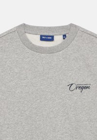 Sweatshirt gris avec col côtelé et tissu texturé. Présente un logo imprimé bleu foncé "Mountain Supply Co. Oregon" à l'avant.