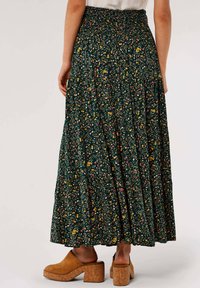 Floral maxi skirt in dark green fabric with gathered waistband; features multicolored flowers, tiered design, and ankle-length cut.