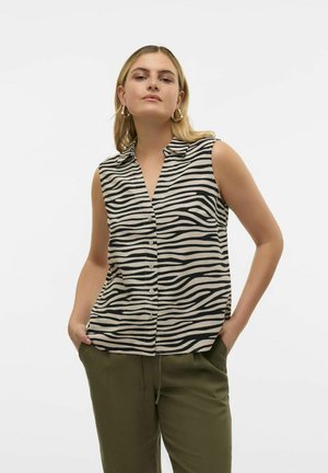 Ženska brezrokavna bluzica v bež barvi z črnimi zebra črtami, z gumbi spredaj in ovratnikom. Model nosi olivno zelene hlače.