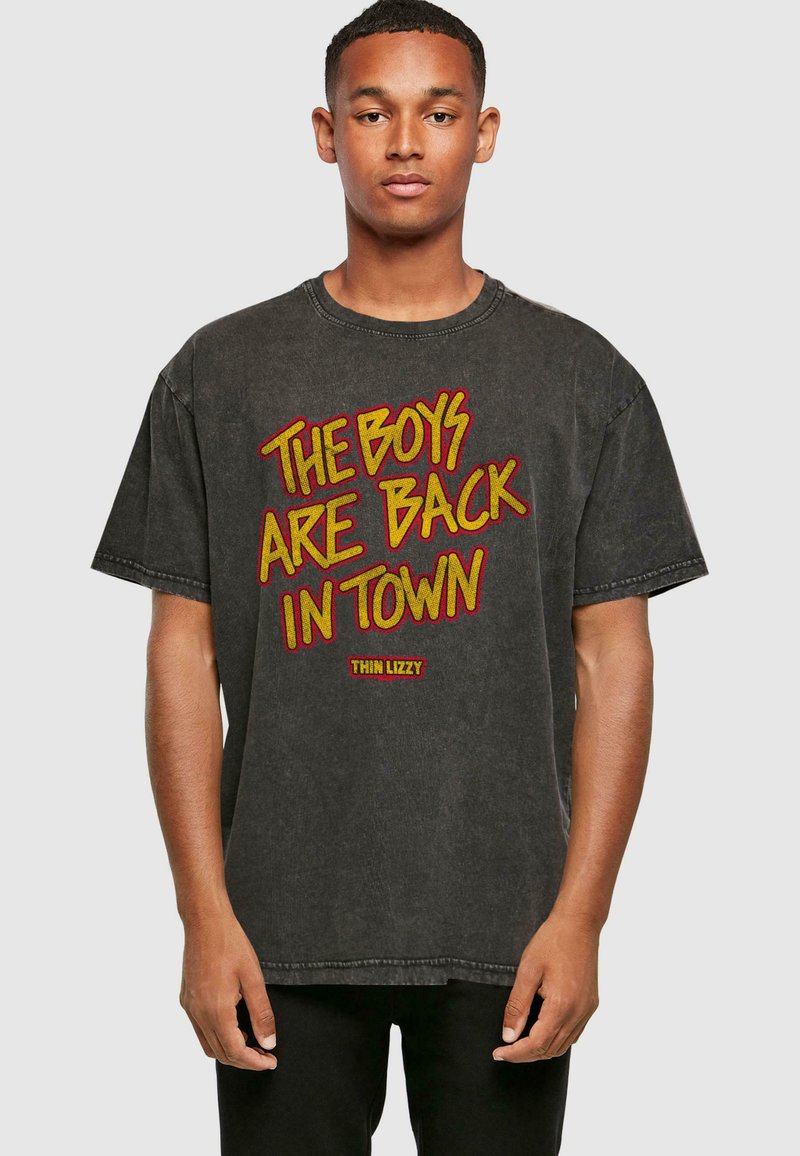 Sort oversized t-shirt i bomuld, med rød og gul grafisk tekst "THE BOYS ARE BACK IN TOWN" fra "THIN LIZZY." Slidt finish.