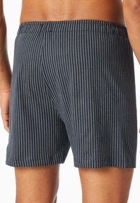 Marineblå stripete boksershorts med elastisk midje, myk stoffkvalitet og minimalistisk design med vertikale hvite striper.