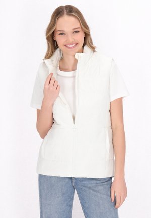 Gilet imbottito bianco senza maniche con colletto alto, chiusura con zip e dettagli di cucitura orizzontale. Abbinato a una t-shirt bianca e jeans.