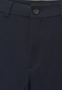 Pantalons taillés bleu marine avec une texture lisse, une fermeture à un bouton et des poches latérales discrètes.