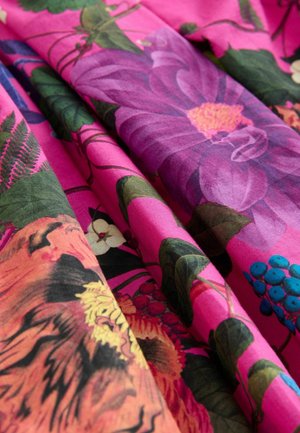 Helles pinkes Gewebe mit großen Blumenmustern in Lila, Orange und Grün, wobei die Texturen von glatt bis leicht strukturiert variieren.