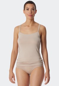 Lys beige top med tynde stropper, lavet af blødt ribbet stof. Har en scoop-udskæring og et tætsiddende design, suppleret af matchende trusser.