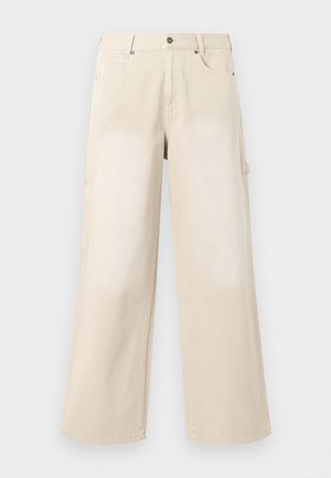 Pantalon beige à jambes larges avec poches avant, fermeture par boutons et passants de ceinture, présenté sur un fond blanc uni.