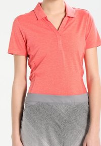 Korálové polo tričko s límcem a zapínáním, vyrobené z lehkého materiálu. Doplněné šedými sportovními šortkami s hladkou texturou a elastickým pasem.