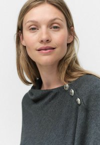 Szary sweter z dekoltem w łódkę, z trzema ozdobnymi metalowymi guzikami na ramieniu, gładka tekstura i luźny krój.