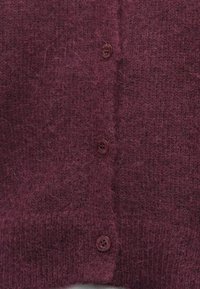Maroon knitted cardigan with a soft, fuzzy texture, featuring four buttons along the front. The fabric has a slightly loose weave.