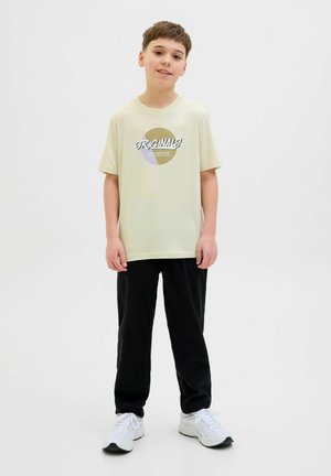 Lichtgroene katoenen t-shirt met "ORIGINALS" grafiek, gecombineerd met zwarte joggingbroek en witte sneakers. Eenvoudig, casual ontwerp.