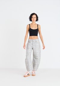 Stijlvolle grijze, patroonte brede pijpenbroek met een hoge taille, gecombineerd met een zwarte, getailleerde crop top en roze sneakers met donkere accenten.