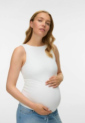 Witte, aansluitende tanktop gemaakt van rekbaar materiaal, gedragen met blauwe jeans. De persoon wiegt een zichtbare zwangere buik.