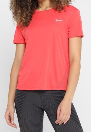 T-shirt sportivo Nike di un brillante colore rosa con maniche corte, caratterizzato da un logo riflettente sul petto e un tessuto leggero e traspirante.