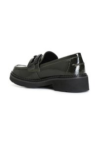 Zapatos de charol verde con una suela negra gruesa, que presentan un lazo decorativo en el empeine y costuras en contraste en los bordes.