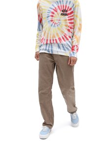 Langärmliges Batik-Shirt mit mehrfarbigem Spiral-Muster; braune cordhosen; hellblaue Sneaker mit weißen Sohlen.