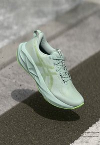 Light mint green athletic shoe with a textured upper, breathable material, reflective accents, and a bright green outsole.