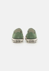 Zelene antilop cipele Converse s niskim profilom, bijelim gumiranim potplatima i detaljem crne pruge. Imaju zaobljen vrh i otkrivene šavove.