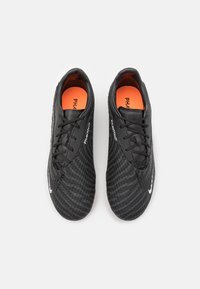 Black soccer shoes with a textured, patterned surface, orange insole, and white logo detail. Features laces and a sleek design.