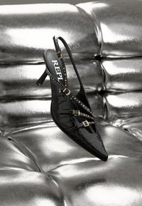 Svart slingback-sko med spiss tå, krokodillemønster, tre justerbare stropper med gullspenner og nagledekorasjoner.