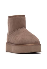 Stivaletto in suede marrone con punta rotonda, dettagli cuciti e suola piatta. Superficie texture e design semplice.