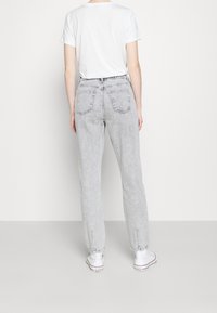 Ljusgrå högmidjade jeans med avslappnad passform, som har bakfickor och en urtvättad textur. Matchas med vita canvas-sneakers.