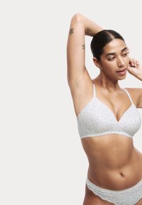 Soutien-gorge blanc avec un motif floral bleu clair, en tissu doux, avec des bonnets sans coutures, des bretelles réglables fines et des culottes assorties bordées de dentelle.